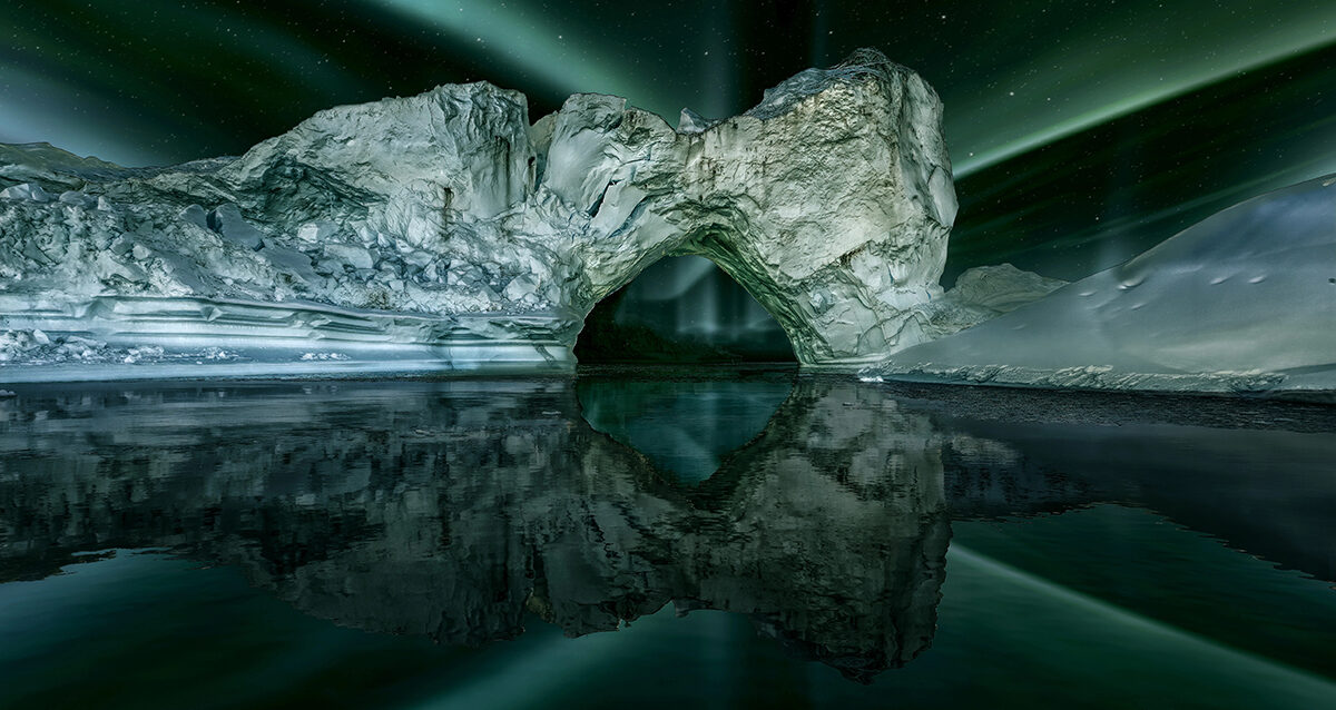iceberg floating in greenland fjord at night with green northern Iceberg in the dark